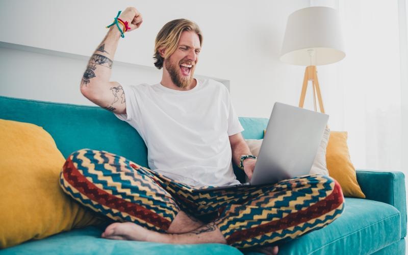 a man sitting on a couch with his mouth open and a laptop