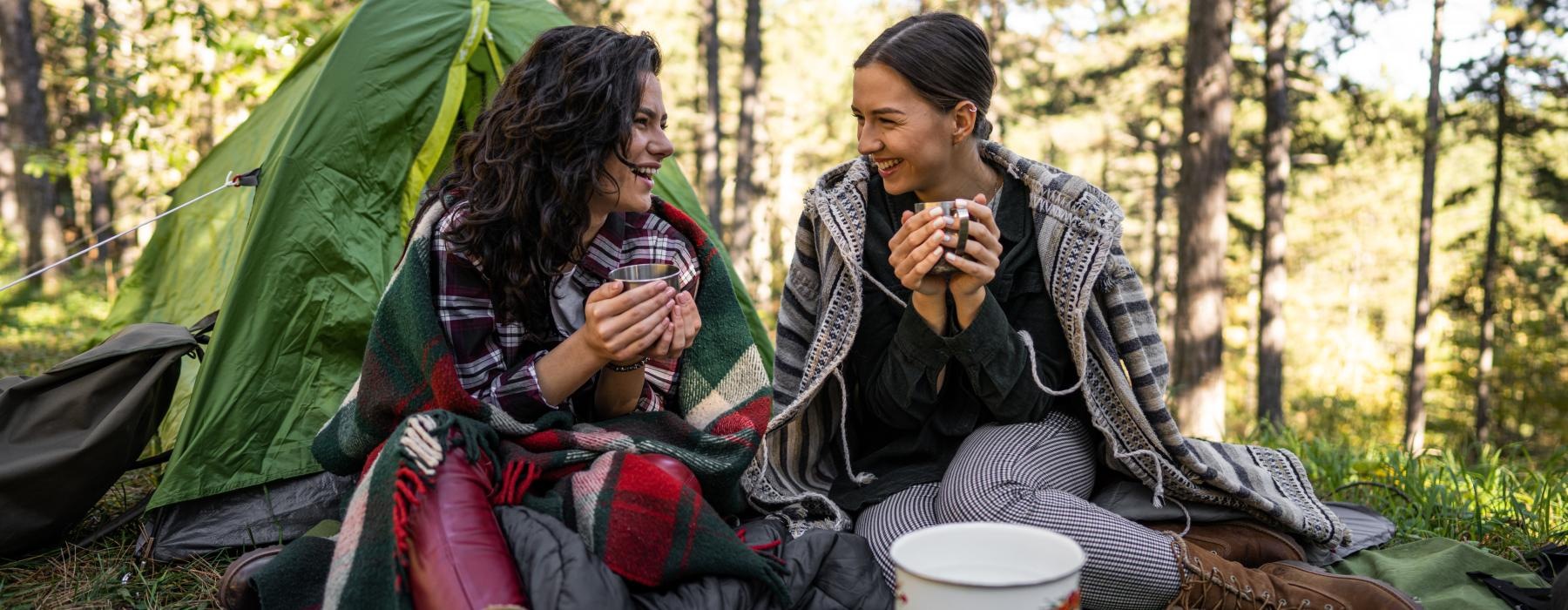 a couple of women sitting on a blanket in the woods