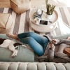 a woman and a dog laying down on a couch in a living room