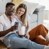 two people sitting down in front of a couch in a living room